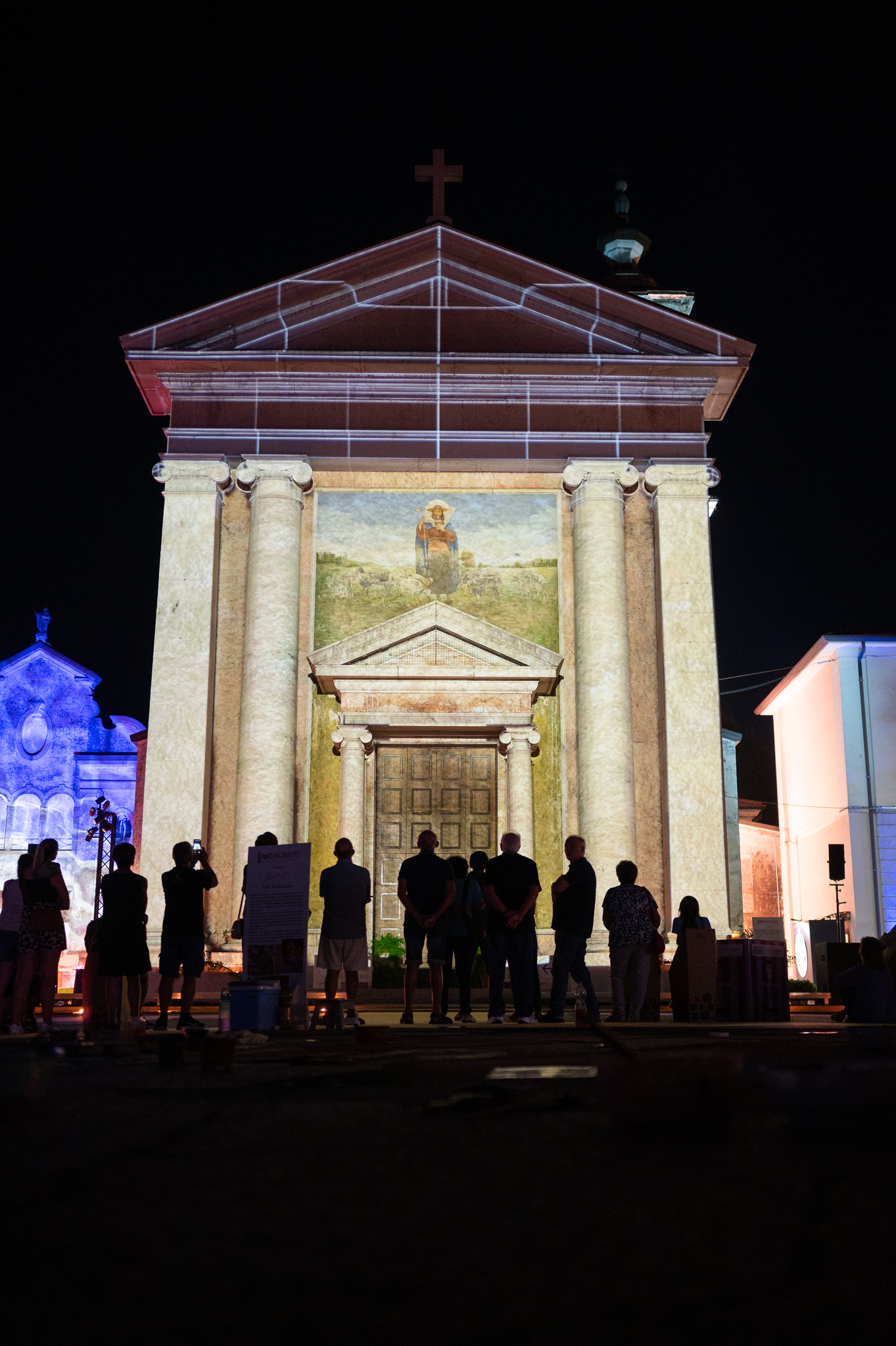 La chiesa di Trevenzuolo illuminata dal videomapping, con il pubblico in controluce